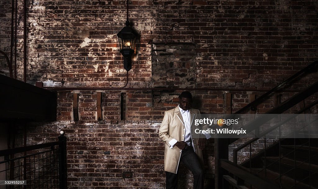 Dapper Young Black Man Wearing Hot Tuxedo in Dark Building