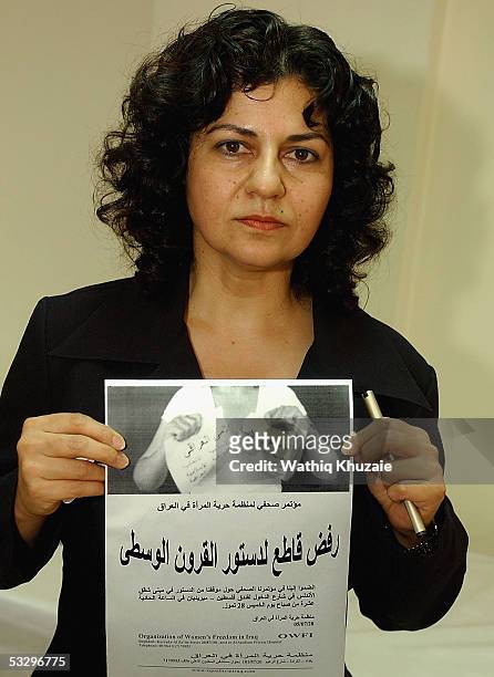 Yanar Mohammed, head of the Women's Freedom in Iraq movement, holds a picture that shows a woman tearing a piece of paper reading "Iraq's Islamic...
