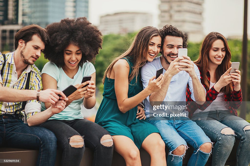 Multi-ethnic group of people with phones outdoors