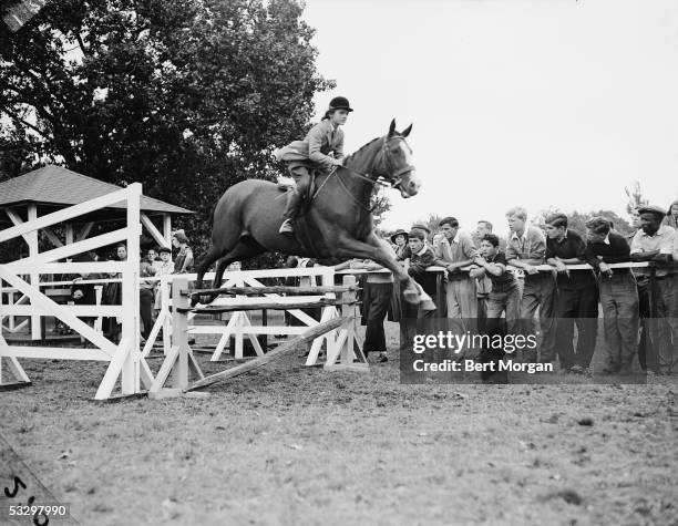 Jacqueline Bouvier jumps her horse, Danseuse, over a fence in a horse show at the Piping Rock Club, Locust Valley, Oyser Bay, Long Island, New York,...