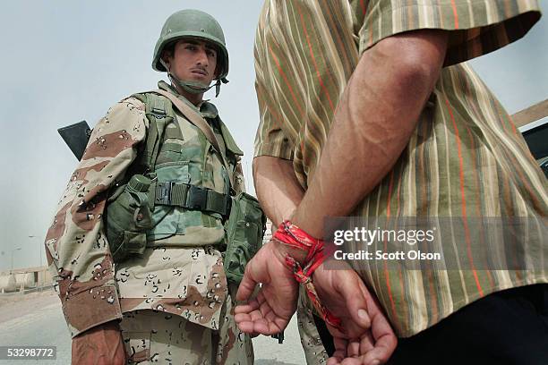 Soldier from the 1st Battalion of the Iraqi Ground Forces Command escorts a prisoner suspected of being an insurgent to a detention center July 28,...