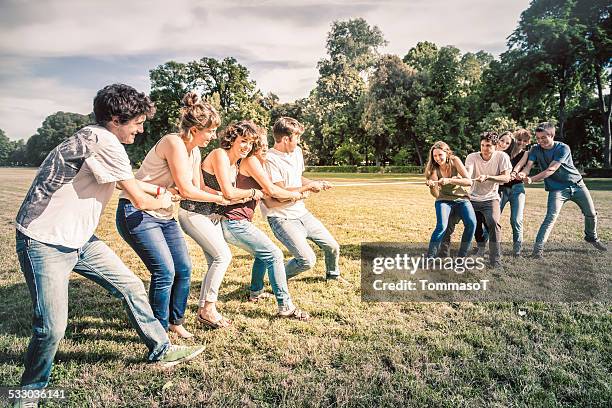 tauziehen-zehn junge freunde im park - tauziehen stock-fotos und bilder
