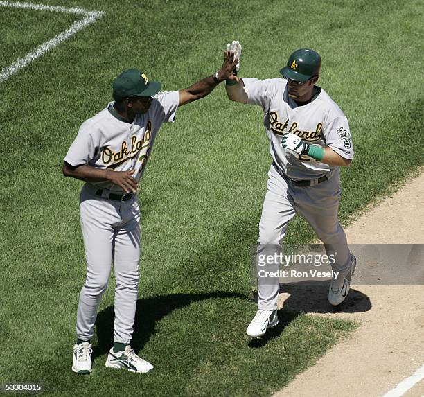 Mark Kotsay of the Oakland Athletics high five's 3rd base coach Ron Washington after Kotsay hit a home run during the game against the Chicago White...