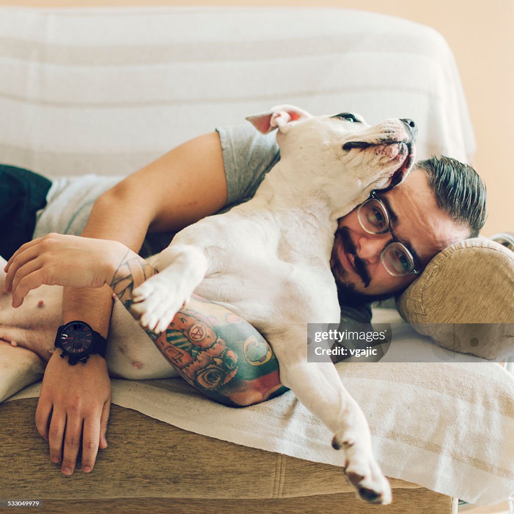 Man with tattoo embracing his dog.