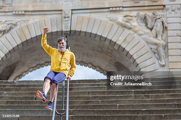 glücklich senior mann rutschen hinunter treppe - sliding stock-fotos und bilder