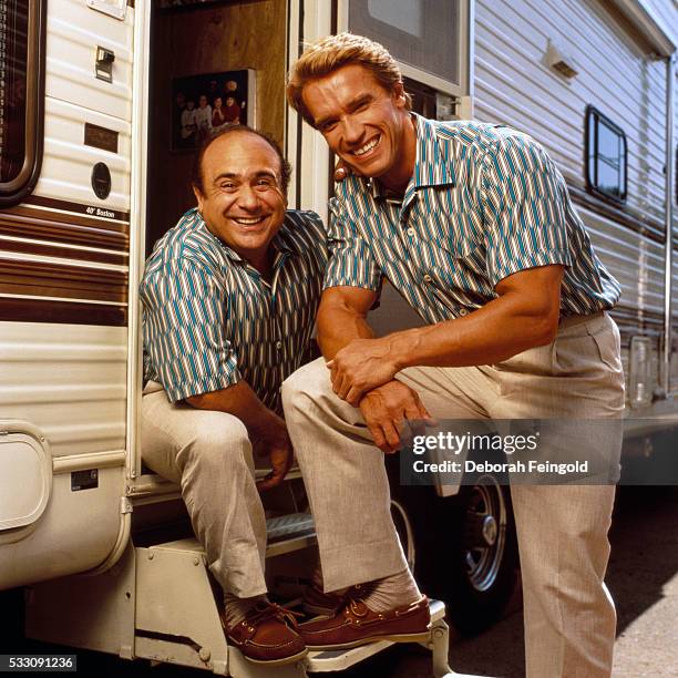 Deborah Feingold/Corbis via Getty Images) Actors Arnold Schwarzenegger and Danny DeVito pose together beside a trailer dressed in matching outfits to...