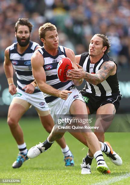 Lachie Henderson of the Cats handballs whilst being tackled by Jesse White of the Magpies during the round nine AFL match between the Collingwood...