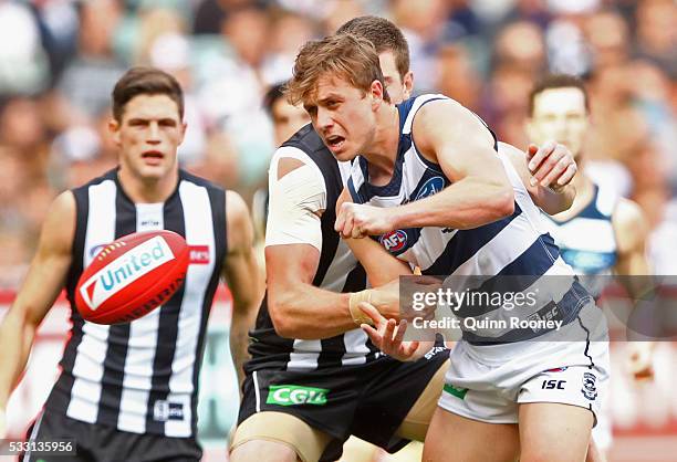 Mitch Duncan of the Cats handballs whilst being tackled by Mason Cox of the Magpies during the round nine AFL match between the Collingwood Magpies...