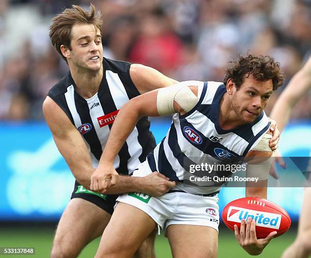 Steven Motlop of the Cats handballs whilst being tackled by Alan Toovey of the Magpies during the round nine AFL match between the Collingwood...