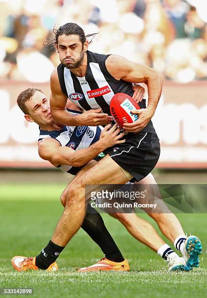 Brodie Grundy of the Magpies handballs whilst being tackled by Joel Selwood of the Cats during the round nine AFL match between the Collingwood...