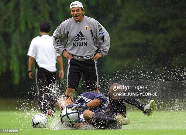 Japan's goalkeeping coach Antonio Cantarele watches goalkeeper Yoshikatsu Kawaguchi hunt down balls in the rain during a practice session for the...