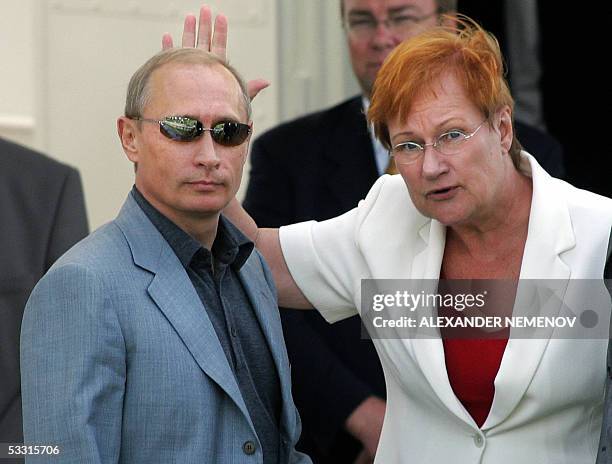 Finnish President Tarja Halonen waves during a sea walk with her Russian counterpart Vladimir Putin after their meeting in Kultaranta presidential...