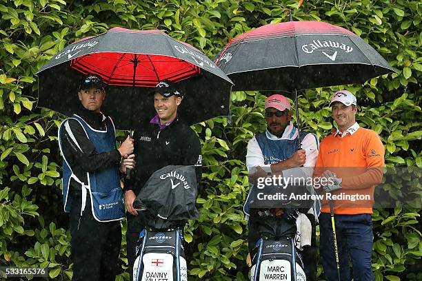 Marc Warren of Scotland and Danny Willett of England shelter from the rain under umbrellas on the 4th tee during the third round of the Dubai Duty...