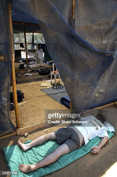 An Israeli youth sleeps inside a makeshift hut set up by settlers for Israeli's opposed to Prime Minister Ariel Sharon's disengement plan who snuck...