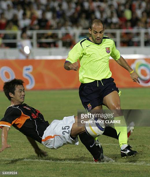 Zhang Yonghai of Shenzhen tackles Gabri Garcia of Barcelona during the first half of a football game between Chinese side Shenzhen Jian Li Bao and FC...