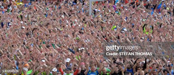 Thousands of amateur athletes wave and dance prior to take part in the traditional Rennsteiglauf fun run marathon across the Rennsteig hiking trail...