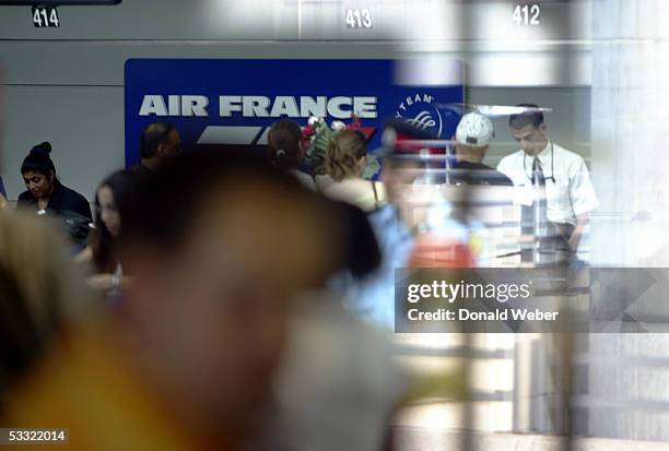 Passengers can be seen checking in for an Air France flight to Paris looking through a window at Pearson International Airport August 3, 2005 in...