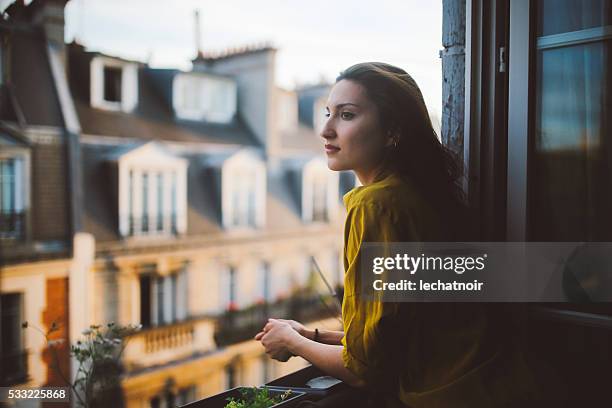 young woman relaxing on the balcony of her montmartre apartment - sassy paris stockfoto's en -beelden