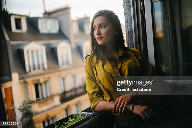 young woman relaxing on the balcony of her parisian apartment - paris balcony stock pictures, royalty-free photos & images