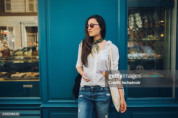 young parisian woman buying in a bakery - walking around the french capital stockfoto's en -beelden