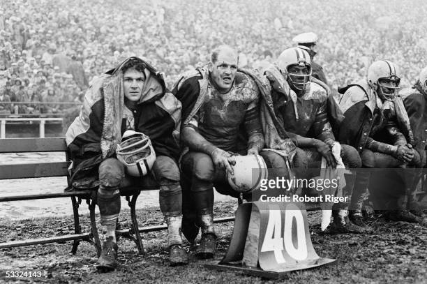 American professional football player Ray Nitschke of the Green Bay Packers sits on the bench with teammates during an away game against the 49ers,...