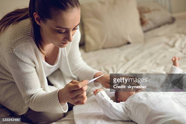preocupado mãe com bebê de temperatura no quarto). - febre imagens e fotografias de stock