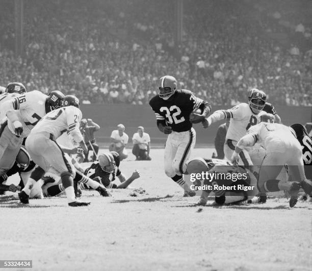 American professional football player Jim Brown of the Cleveland Browns runs with the ball towards the defensive line of the New York Giants,...