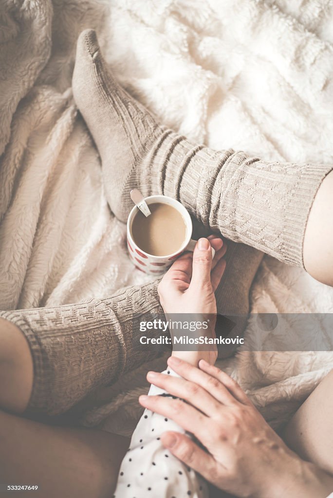 Female legs in knitted socks with cup of  coffee