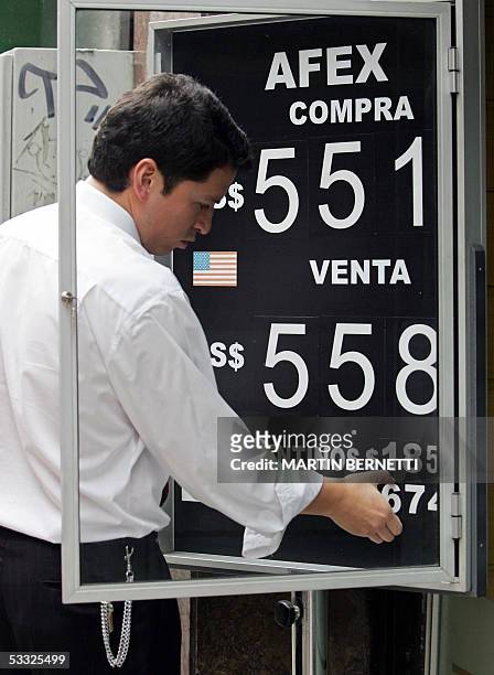 Un empleado cambia la cotizacion del dolar estadounidense en una cartelera de una casa cambiaria en el centro de Santiago el 04 de agosto de 2005. La...