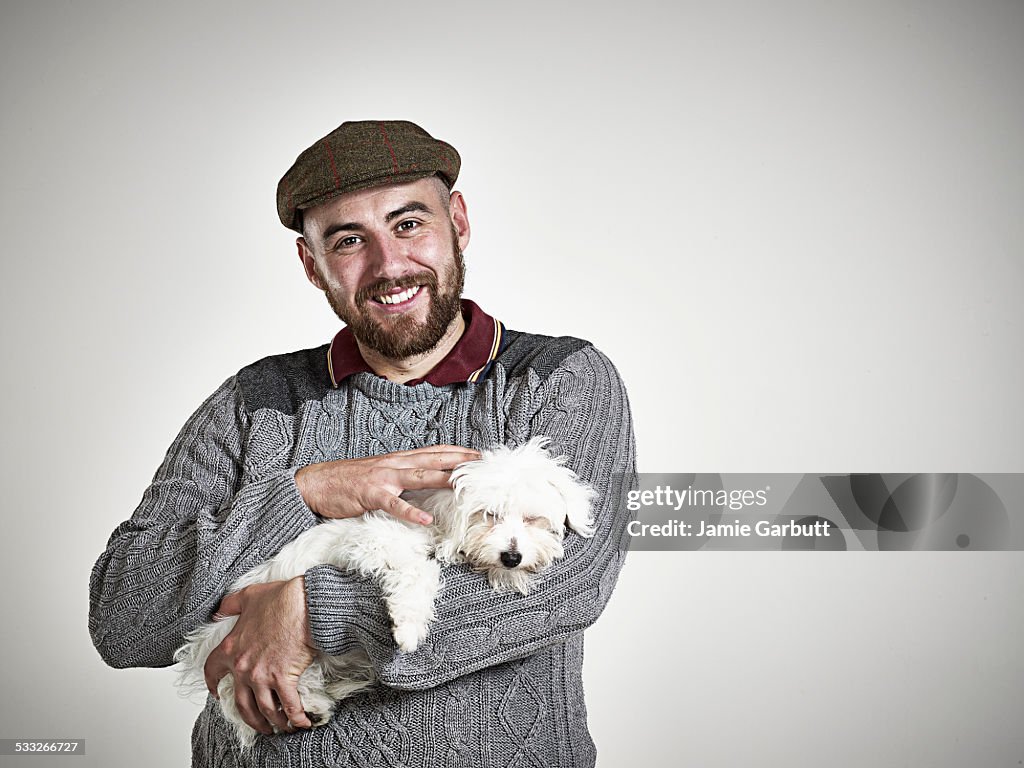 Breaded male smiling whilst stroking a puppy