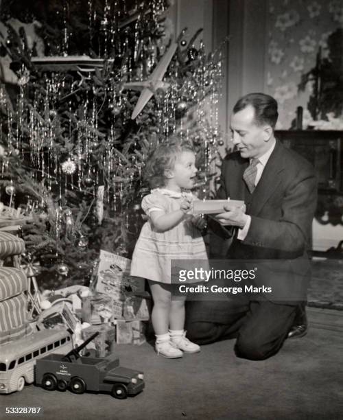 father & daughter w/toy in front of christmas tree - christmas tree 50's stockfoto's en -beelden