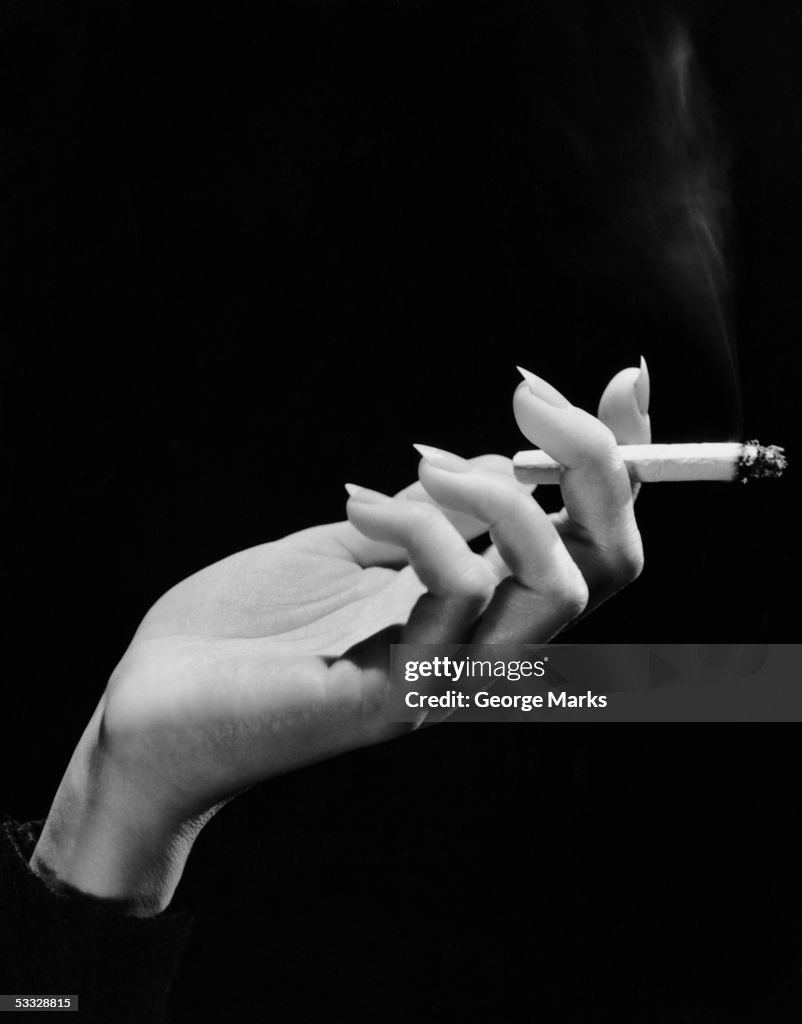 Woman's hand holding lit cigarette