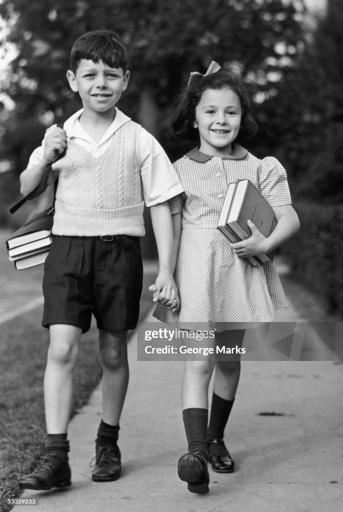 Young girl & boy walking to school w/ books