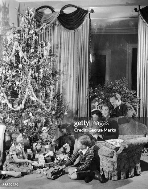 family gathered around christmas tree with gifts - christmas tree 50's stockfoto's en -beelden