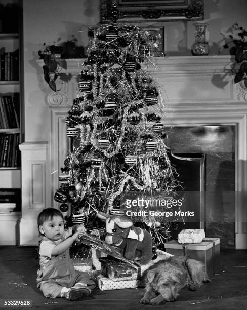 baby beside a christmas tree - christmas tree 50's stockfoto's en -beelden
