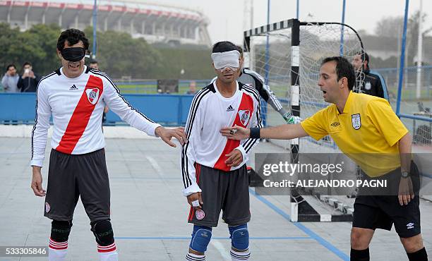 The Argentinian referee gives instructions to River Plate's footballers Oscar Mouzo and Gustavo Maidana during a blind football match of the...
