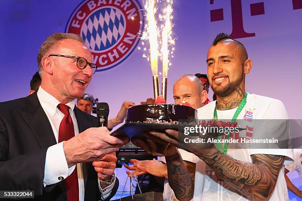 Karl-Heinz Rummenigge, CEO of Bayern Muenchen, hands over a birthday cake to his player Arturo Vidal during the FC Bayern Muenchen champions party at...