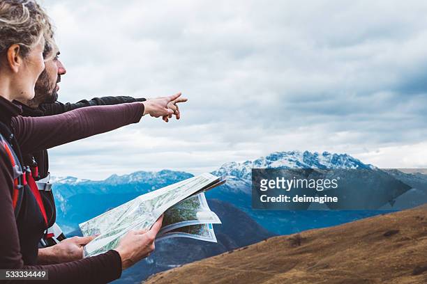 hiking couple with map in mountain - direction stock pictures, royalty-free photos & images