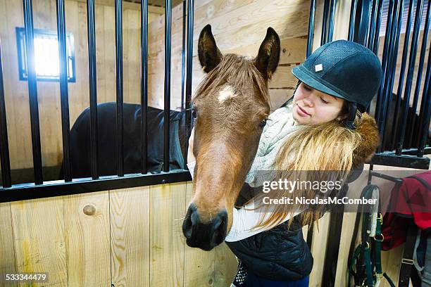 teenage girl in riding gear stroking her horse in stall - teen group therapy stock pictures, royalty-free photos & images