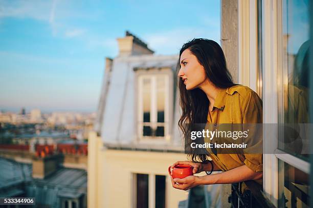 young woman relaxing on the balcony of her parisian apartment - paris balcony stock pictures, royalty-free photos & images