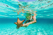 woman with snorkel and mask holding a starfish