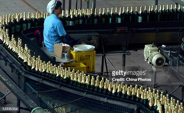 An employee works at the beer production line in Guangzhou Zhujiang Beer Group Company factory on August 6, 2005 in Guangzhou of Guangdong Province,...