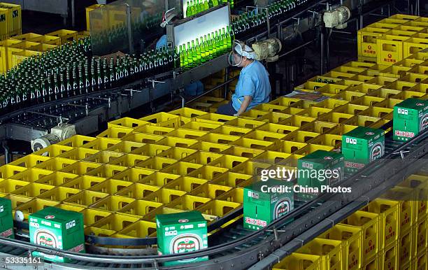 An employee works at the beer production line in Guangzhou Zhujiang Beer Group Company factory on August 6, 2005 in Guangzhou of Guangdong Province,...