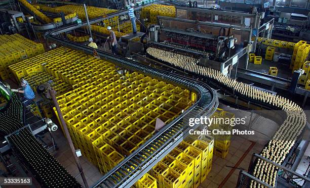 Employees work at the beer production line in Guangzhou Zhujiang Beer Group Company factory on August 6, 2005 in Guangzhou of Guangdong Province,...