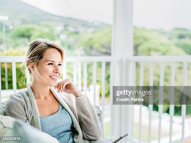 happy young woman relaxing on balcony - mid adult stock pictures, royalty-free photos & images