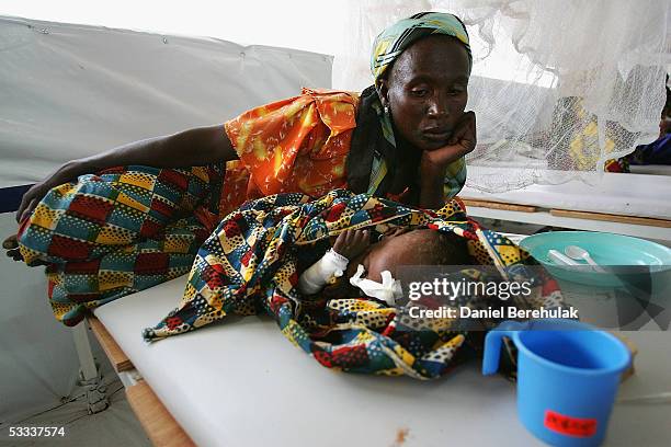 Mother watches her malnourished baby sleeping after receiving treatment at an MSF clinic on August 7, 2005 in Aguie, Niger. These clinics, though few...