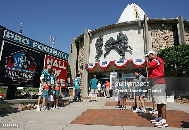 Fans pose for pictures in front of the Pro Football Hall of Fame before the 2005 NFL Hall of Fame enshrinement ceremony on August 7, 2005 in Canton,...