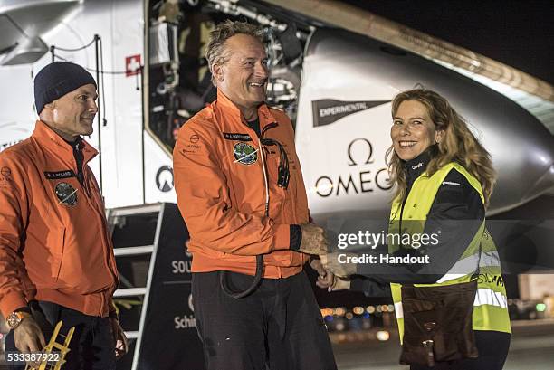 In this handout image supplied by SI2, Swiss adventurer Andre Borschberg is welcomed by his wife Yasemin and alternate pilot Bertrand Piccard after...