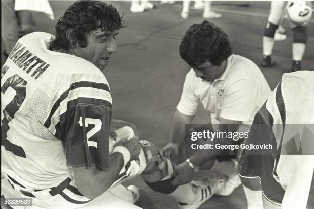 Quarterback Joe Namath of the New York Jets sits on the bench as his knee brace is adjusted during a preseason game against the Pittsburgh Steelers...