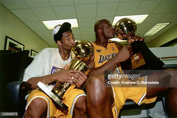 Kobe Bryant and Shaquille O'Neal of the Los Angeles Lakers sit with the NBA Championship Trophy and the Playoff MVP Trophy after winning the 2000 NBA...